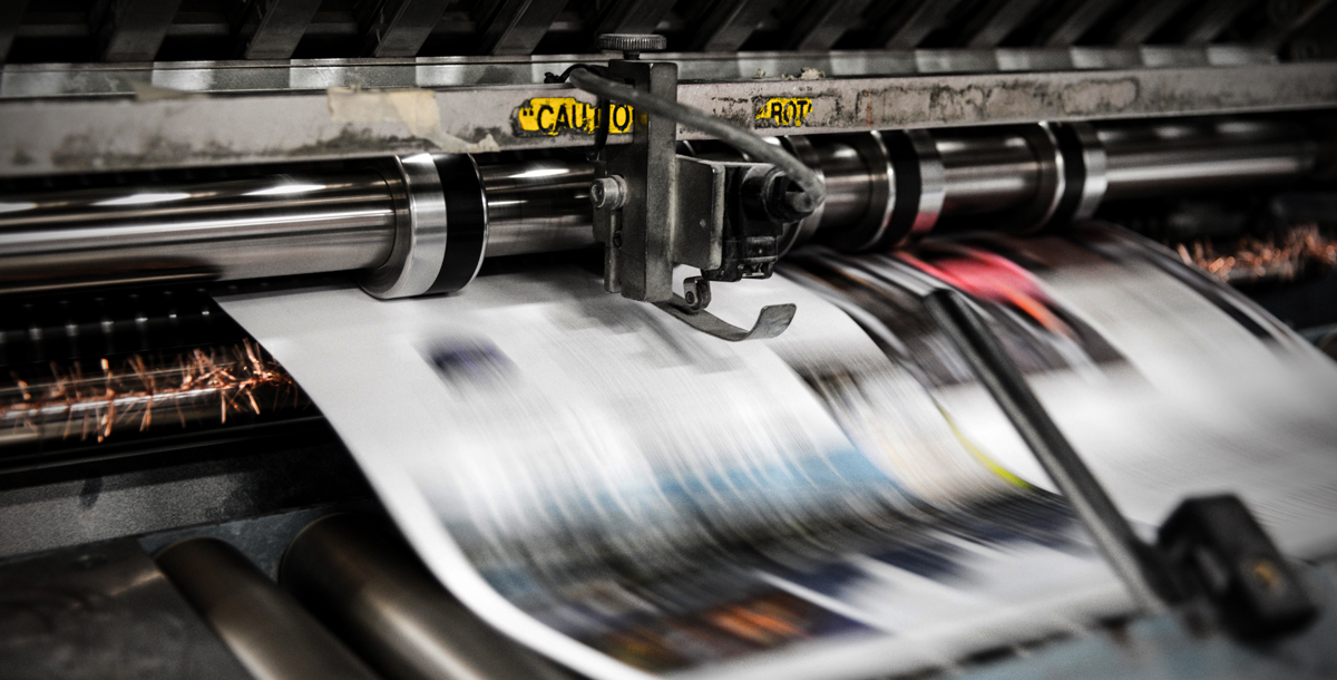 Image showing a printing press with paper flying by very quickly, representing the speed and efficiency that Conquest Graphics has worked to improve continually through print automation.